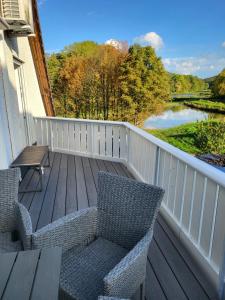 Un balcón con 2 sillas, una mesa y un río en Ferienwohnung Deichblick en Gerhardshofen