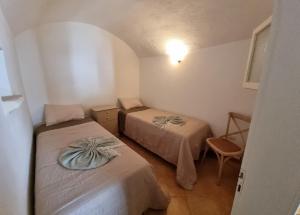 レウカにあるCasa a Santa Maria di Leucaのベッド2台と椅子が備わる小さな客室です。