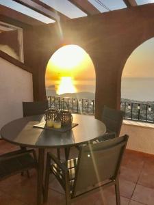 una mesa y sillas en un balcón con vistas a la puesta de sol en VISTA SUPERIOR hola ZEEZICHT!! en Cumbre del Sol