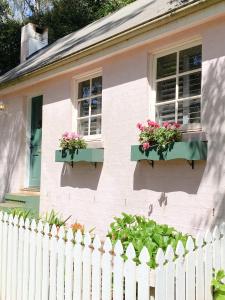 a white house with flowers in windows and a fence at Enchanting Retreat - The English Cottage at Tamborine Mountain in Mount Tamborine