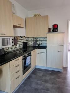 eine Küche mit weißen Schränken und schwarzen Arbeitsplatten in der Unterkunft Ferienwohnung in Fuldatal bei Kassel in Fuldatal + 22 Fotos