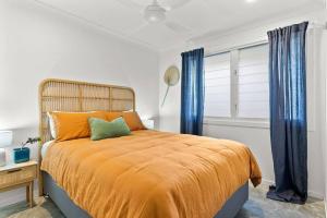a bedroom with a large bed with blue curtains at Salty Crab Bungalow in Lennox Head