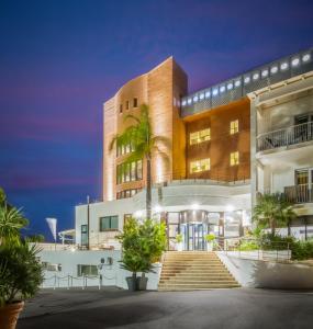 a building with a palm tree in front of it at Hotel Kalura in Cefalù