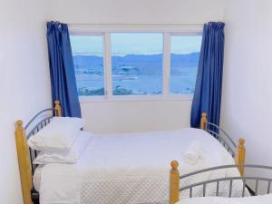 een slaapkamer met een bed en een groot raam bij NO PARTY ALLOWED,Sea view 5 bedroom house in Wellington