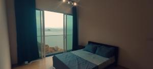 ein Schlafzimmer mit einem Bett und einem großen Fenster in der Unterkunft Infinite Seaview with Penang Bridge Suite with Sunrise up to 11 person in Bayan Lepas
