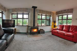 a living room with a red couch and a fireplace at Stunning 2 Bedroom Guest House with Hot Tub in Durham