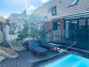 un patio avec deux chaises et une piscine dans l'établissement Appartement proche Astérix, Stade de France, Chantilly, Roissy, piscine saisonnière, à La Chapelle-en-Serval