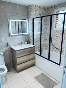 a bathroom with a tub and a sink and a toilet at Appartement proche Astérix, Stade de France, Chantilly, Roissy, piscine saisonnière in La Chapelle-en-Serval