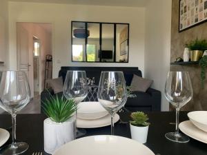 a dining room with wine glasses on a table at Appartement proche Astérix, Stade de France, Chantilly, Roissy, piscine saisonnière in La Chapelle-en-Serval