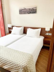 1 dormitorio con 2 camas con sábanas blancas en Flores Lofts, en Oporto