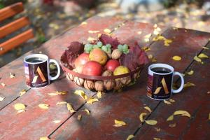 eine Schale Obst auf einem Tisch mit zwei Tassen in der Unterkunft 1st Apartment in Nehoiu