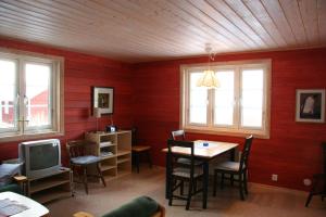 uma sala de jantar com paredes vermelhas e uma mesa e uma televisão em Hornborgasjöns Stugby em Bjällum