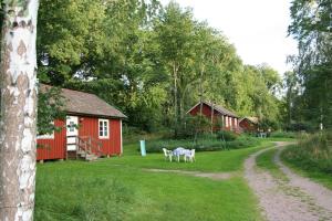 um celeiro vermelho com um parque infantil no quintal em Hornborgasjöns Stugby em Bjällum