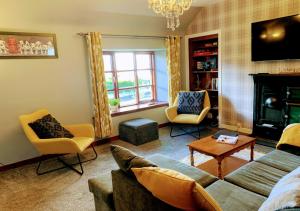 a living room with a couch and chairs and a fireplace at Burnside Cottages in Fettercairn