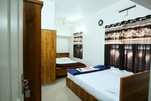 a bedroom with two beds and a door at Hillside Hideaway Gudalur in Gūdalūr