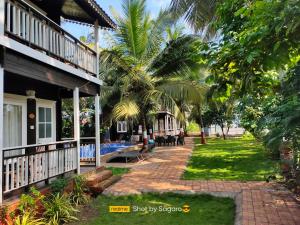 ganek domu z palmami obok niego w obiekcie Casa Seaesta Beach Cottages and Suites w mieście Arambol