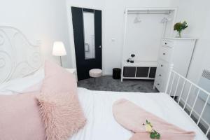 1 dormitorio con cama blanca y almohadas rosas en Central Gunwharf Quays Two Bedroom apartment, en Portsmouth