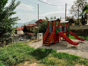 a playground with a red slide in a yard at Elena Guesthouse in Kalabaka