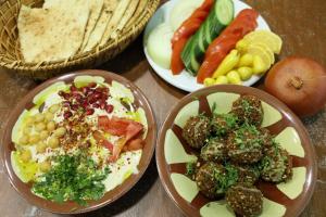 a table with plates of food and baskets of vegetables at Friends Hostel.Area B in Hebron