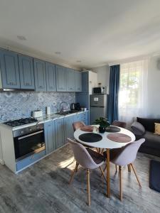kuchnia z niebieskimi szafkami oraz stołem i krzesłami w obiekcie Apartament Alex w Sybinie