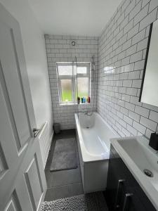 a white bathroom with a tub and a sink at Castle Court Apartment in London