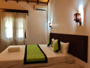 希卡杜瓦的住宿－Sundowners Guesthouse，一间卧室配有一张带绿色床单的床和一扇窗户。