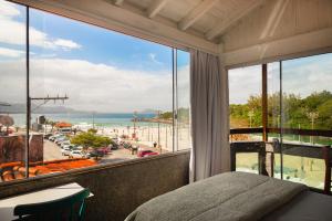 a bedroom with a view of the beach and the ocean at Sea Wolf Surf Hostel in Florianópolis