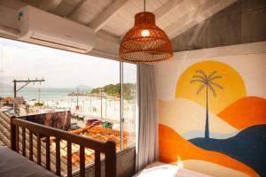 a bedroom with a view of the beach from a window at Sea Wolf Surf Hostel in Florianópolis