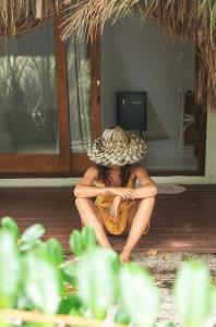a woman sitting on the floor wearing a hat at Pousada Casa Marae in Caraíva