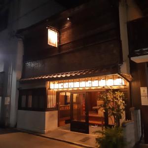 ダース旅館＆カフェ（Dozen-Ryokan＆Cafe） في Nishi-kujō-Toriiguchichō: مبنى به مدخل مضاء في الليل