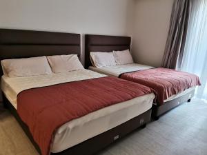 Duas camas sentadas uma ao lado da outra num quarto em By The Sea Batu Ferringhi Beach Front Apartment Suite em Batu Ferringhi