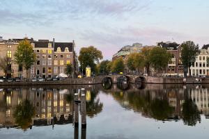 een rivier in een stad met gebouwen en een brug bij SWEETS Walter Süskindbrug in Amsterdam