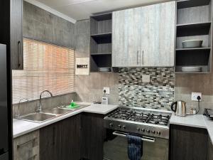 a kitchen with a stove and a sink at UStay Apartment - Westdene in Bloemfontein