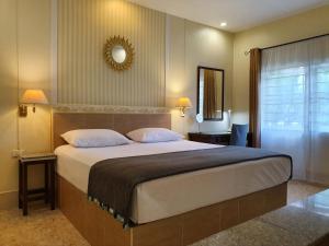 a bedroom with a large bed and a mirror at Holiday Village And Natural Garden Resort in Karon Beach