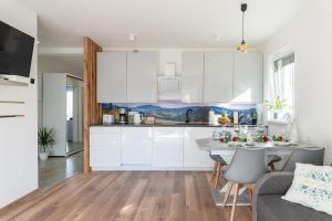 a kitchen and living room with white cabinets and a table at Apartamenty Pod Cisem Lux in Kudowa-Zdrój