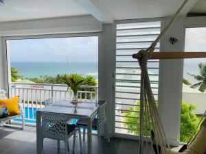 a porch with a hammock and a table on a balcony at Le 35 Anse des Rochers Saint-François in Saint-François