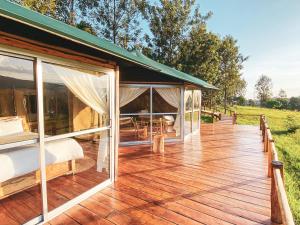 Haus mit einer Terrasse mit einem Bett und Fenstern in der Unterkunft Foresight Eco Lodge & Safari in Karatu