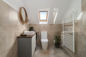 een badkamer met een toilet, een wastafel en een spiegel bij Kapocs Apartmanház in Borgáta