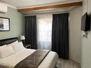UStay Apartment - Westdene في بلومفونتين: غرفه فندقيه بسرير ونافذه