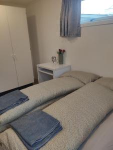 two beds in a room with a table and a window at FeelHome 2 bedrooms apartment Vidarsveg in Tromsø