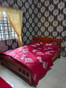 1 dormitorio con cama roja y edredón rojo en Homestay Hassani en Kepala Batas