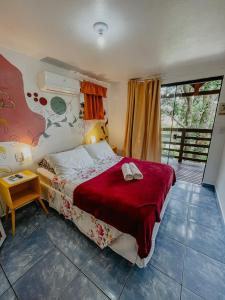1 dormitorio con 1 cama grande con manta roja en Pousada Praia de Bombinhas, en Bombinhas