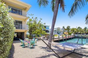 a hammock with chairs and a table next to a pool at The Salty Seahorse in Key Colony Beach