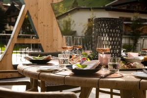 a wooden table with plates of food and wine glasses at das Alois 4 Sterne Superior in Tux