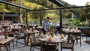 Um homem está a pôr as mesas num restaurante. em das Alois 4 Sterne Superior em Tux