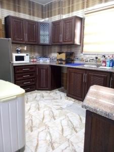 a kitchen with wooden cabinets and a marble floor at Furnished apartment for rent in jarash شقة مفروشة للإيجار في جرش in Jerash