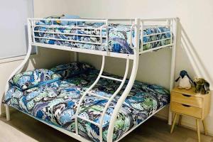 a white bunk bed with a blue and white comforter at Racing Penguin Surf Grand Prix Walk Phillip Island in Sunset Strip