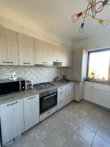 a kitchen with white cabinets and a stove top oven at Cozy Apartment - near Airport and Palas Mall in Iaşi