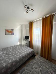 a bedroom with a bed and an orange curtain at Cozy Apartment - near Airport and Palas Mall in Iaşi