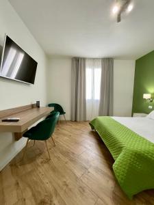 a bedroom with a bed and a desk with a green bedspread at ALBARIA ROOMS-APARTMENTS in Marsala